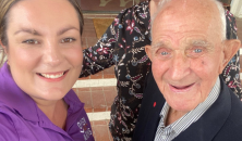 A woman and elderly man pose for a selfie