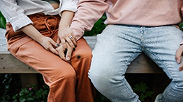 Two people sitting with one person holding the hand of the other