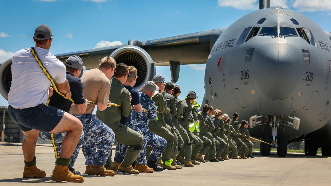 ADF members pull an Air Force plane with a rope