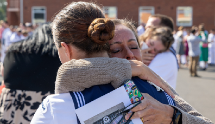 Two women hug, one wearing a navy uniform